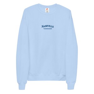 May include: A light blue sweatshirt with the text "NASHVILLE TENNESSEE" in navy blue.