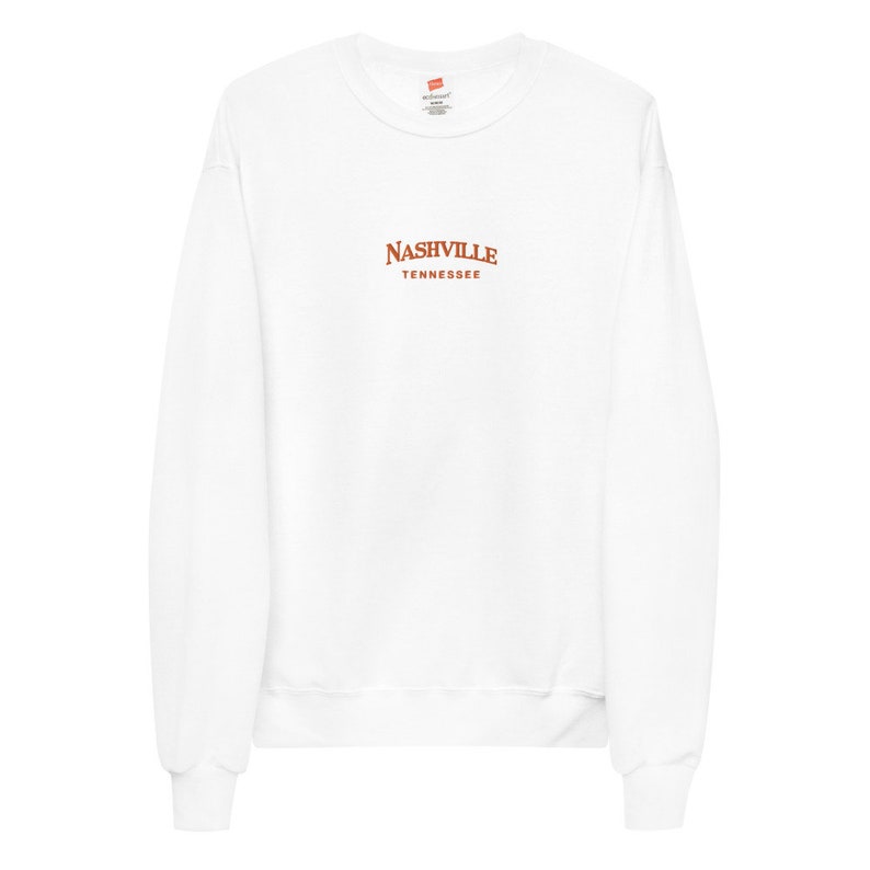 May include: White long-sleeve sweatshirt with a brown embroidered design that says "NASHVILLE TENNESSEE".