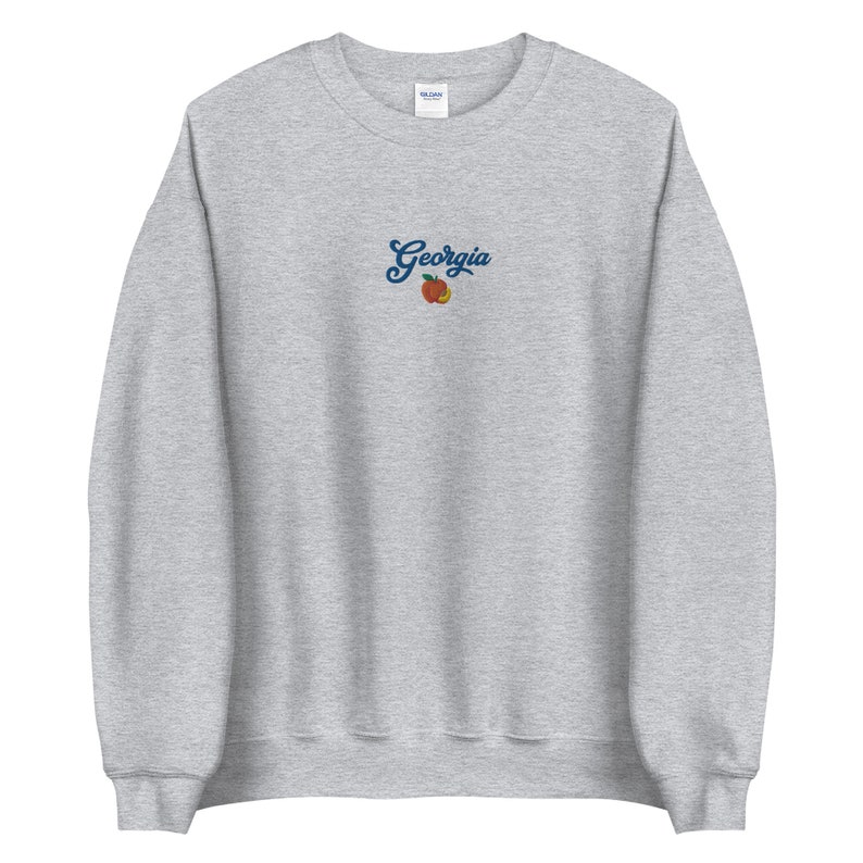 K&ouml;nnte beinhalten: Grauer Sweatshirt mit einem Pfirsich und dem Wort "Georgia" auf der Vorderseite gestickt.
