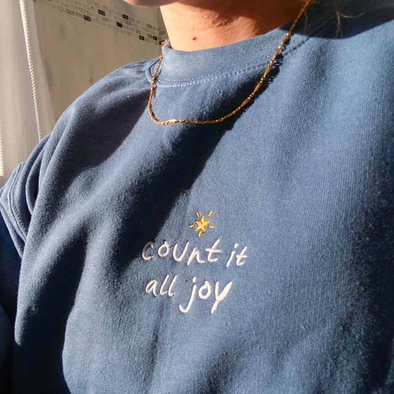 May include: A blue sweatshirt with the text "count it all joy" embroidered in white with a small yellow star above the text.