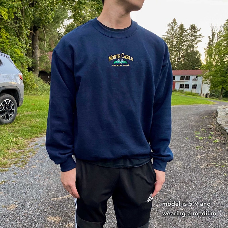 May include: A navy blue sweatshirt with a white embroidered logo that says "Monte Carlo Country Club".