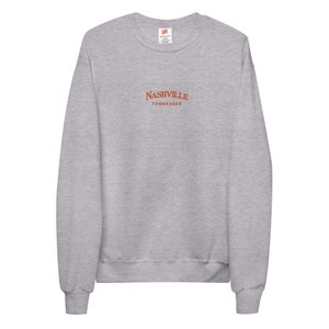 May include: A heather gray sweatshirt with a red embroidered design that says "NASHVILLE TENNESSEE".