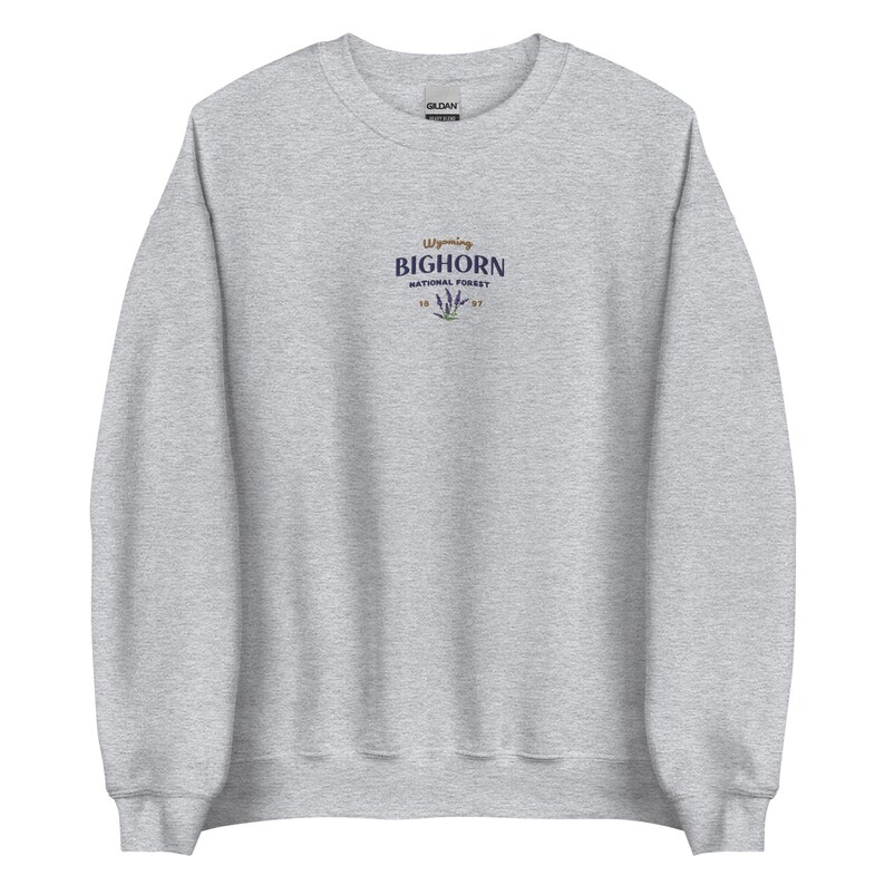 May include: A heather grey sweatshirt with a small embroidered logo on the front. The logo says "Wyoming Bighorn National Forest" with a stylised flower design.