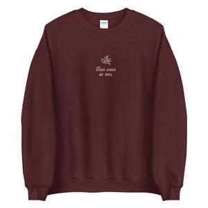 Puede incluir: Una sudadera color granate con un dise&ntilde;o bordado en blanco de un p&aacute;jaro y el texto "Then Sings My Soul".