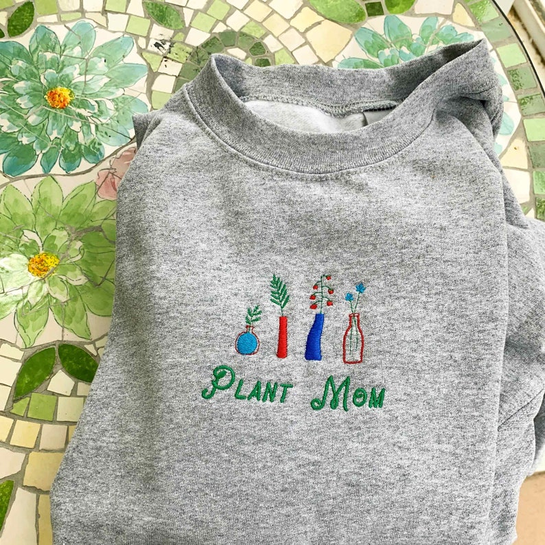 May include: Gray sweatshirt with embroidered plants in vases and the text "PLANT MOM".