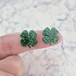May include: A pair of green glitter four-leaf clover earrings.