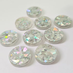 May include: Ten iridescent white round embellishments with a hole in the center. The embellishments are made of small pieces of iridescent material.