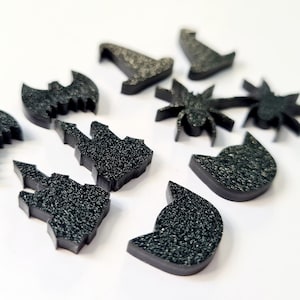 May include: A set of black Halloween-themed felt cutouts, including a witch's hat, a bat, a spider, a castle, a cat, and a palm tree.