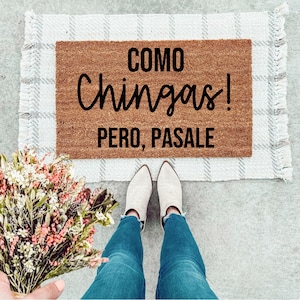 May include: A brown coir doormat with the text "COMO CHINGAS! PERO, PASALE" in black lettering.