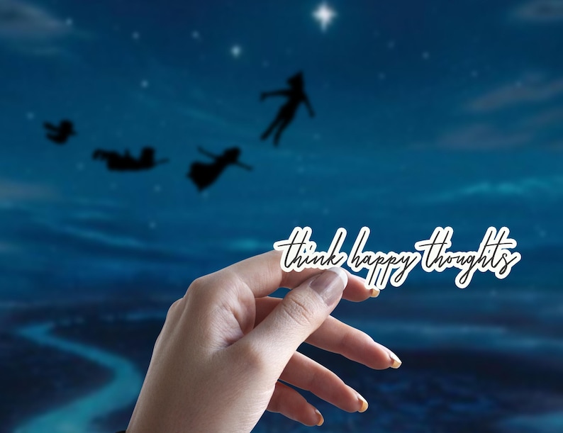 May include: A white sticker with the text "Think happy thoughts" in black script font. The sticker is held in a hand against a blue background with silhouettes of people flying.