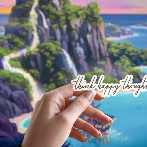 May include: A white sticker with the text "think happy thoughts" written in black cursive script. The sticker is being held in front of a cartoon image of a tropical island with a waterfall.