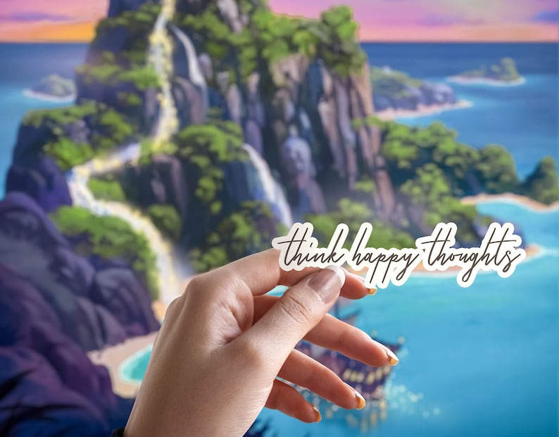 May include: A white sticker with the text "think happy thoughts" written in black cursive script. The sticker is being held in front of a cartoon image of a tropical island with a waterfall.