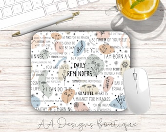 May include: A rectangular mouse pad featuring a white background with black text, floral line art, and soft-colored abstract shapes. The text includes phrases like Daily Reminders, Be You, You Are Loved, and A Grateful Heart Is A Magnet For Miracles.