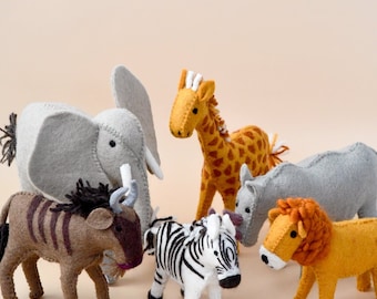 May include: A set of felt animal toys, including a zebra, giraffe, lion, elephant, rhino, and wildebeest. The toys are all made of felt and have a soft, cuddly texture.