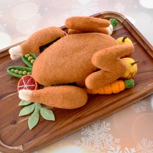 May include: A felt turkey with drumsticks, vegetables, and fruit on a wooden serving tray. The turkey is brown, with white accents on the drumsticks. Green peas, orange carrots, and yellow apples are also included.