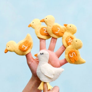 May include: Five yellow felt finger puppets shaped like chicks with numbers 1 through 5 on them. A white felt finger puppet shaped like a chick with closed eyes is on the thumb.