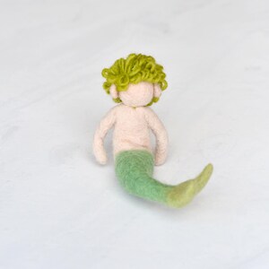May include: A hand-felted green mermaid with a curly green hair and a light pink torso.