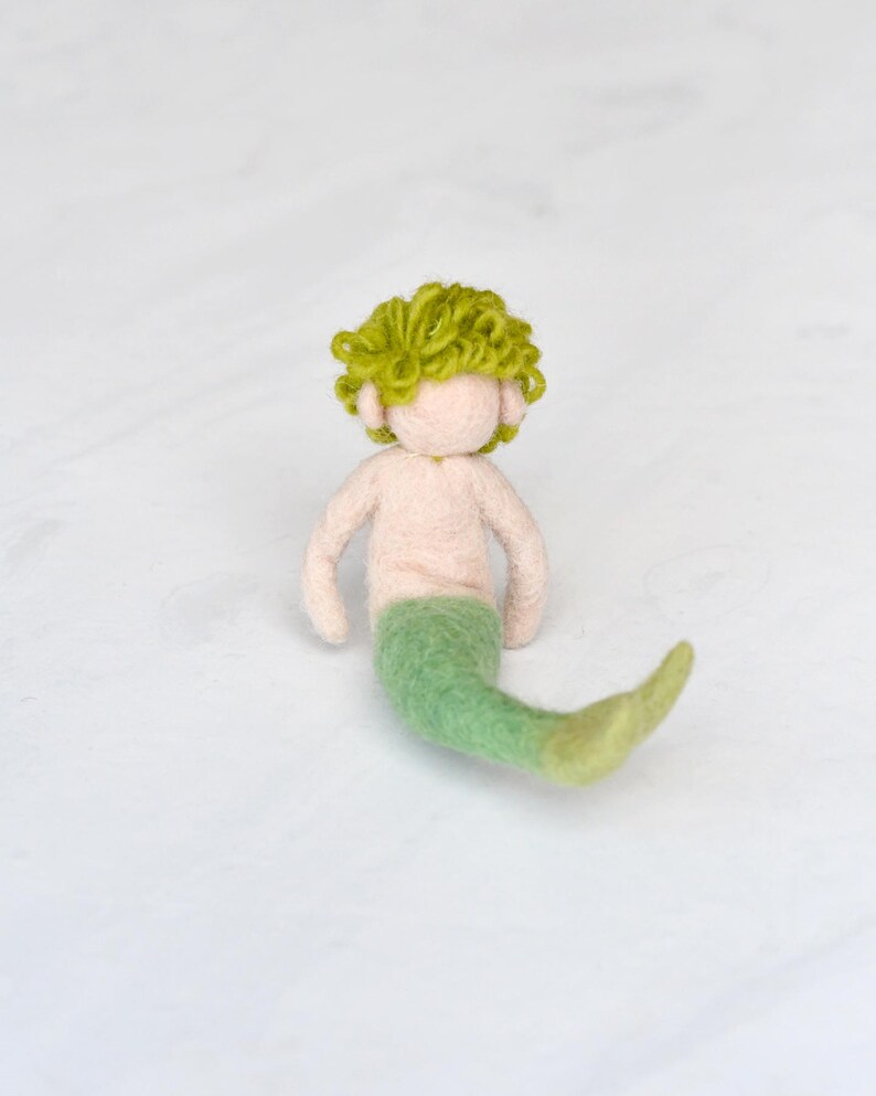 May include: A hand-felted green mermaid with a curly green hair and a light pink torso.