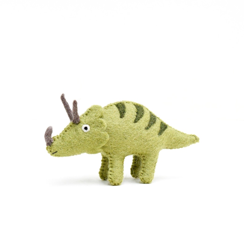 May include: A green felt triceratops toy with brown horns and a white eye. The toy has a striped pattern on its back.