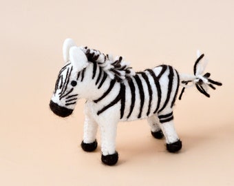 May include: A small, white and black felt zebra toy. The zebra has a black mane and tail.
