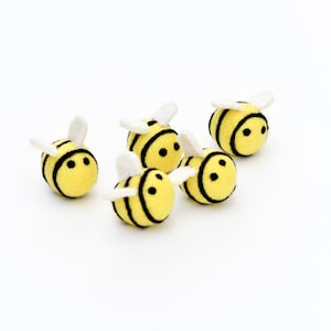 May include: Five felt bumblebees with black and white wings and black eyes. The bumblebees are yellow with black stripes.