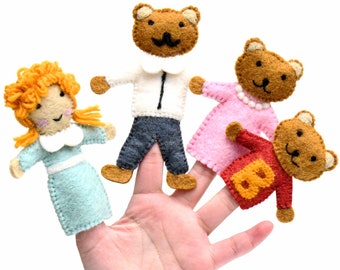 Könnte beinhalten: Vier Fingerpuppen aus Filz: ein Mädchen mit roten Haaren, ein brauner Bär mit einem weißen Hemd und einer blauen Hose, ein brauner Bär mit einem rosa Kleid und ein brauner Bär mit einem roten Hemd mit einer gelben Nummer 8.