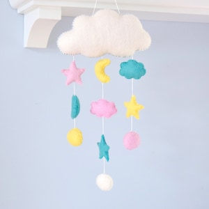 May include: A white felt cloud mobile with pink, yellow and blue felt stars, moons and clouds hanging from it.