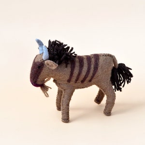 Może przedstawiać: Pluszowa zabawka w kształcie gnu w kolorze brązowym i czarnym z niebieskimi rogami. Zabawka ma długi ogon z czarnym futrem.