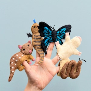 May include: A hand wearing five felt finger puppets: a brown and white spotted cat, a brown and black striped lizard, a blue and black butterfly, a white and cream mouse, and a brown snake.