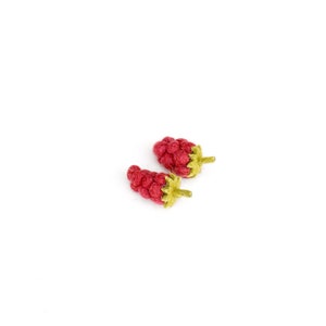 May include: Two felt raspberries with green stems. The raspberries are a deep red color and are arranged side by side on a white background.
