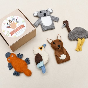 May include: A set of six felt finger puppets featuring Australian animals. The puppets include a koala, a kangaroo, an emu, a kookaburra, a platypus, and a wombat. The puppets are packaged in a brown cardboard box with a label that reads "Australiana Finger Puppets".
