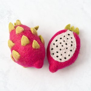May include: Two felt dragon fruit toys. One is pink with green accents and the other is pink with a white center and black seeds.