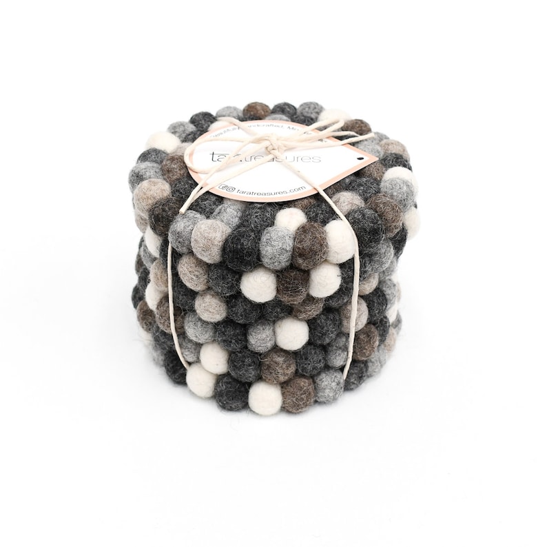 May include: Set of six gray, brown, and white felt coasters with a textured ball design. The coasters are stacked and tied together with twine. The label reads "Tara Treasures".