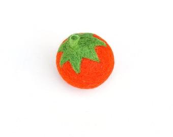 Può includere: Un pomodoro di feltro con un gambo e una foglia di feltro verde. Il pomodoro è di colore arancione brillante.