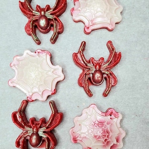 May include: Six red and white Halloween-themed wax melts, three are spider shapes and three are spiderwebs.