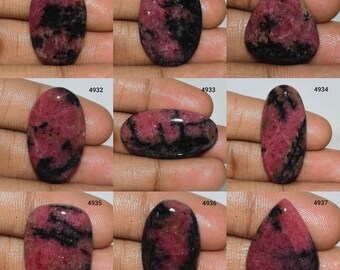 May include: Nine oval and teardrop shaped cabochon gemstones with pink and black patterns. The gemstones are arranged in a grid of three rows and three columns.