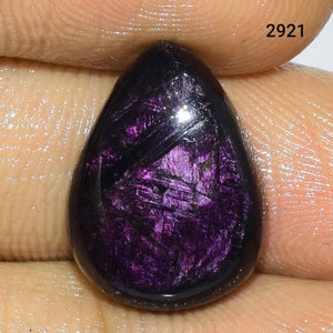 Puede incluir: Una piedra preciosa p&uacute;rpura en forma de l&aacute;grima con un brillo iridiscente oscuro. La piedra tiene un patr&oacute;n estriado &uacute;nico.