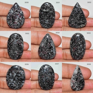 Peut inclure: Dix cabochons de pierres précieuses de différentes formes et tailles. Les pierres sont un mélange de noir, de blanc et de rose avec un motif moucheté. Les pierres sont numérotées de 3050 à 3058.