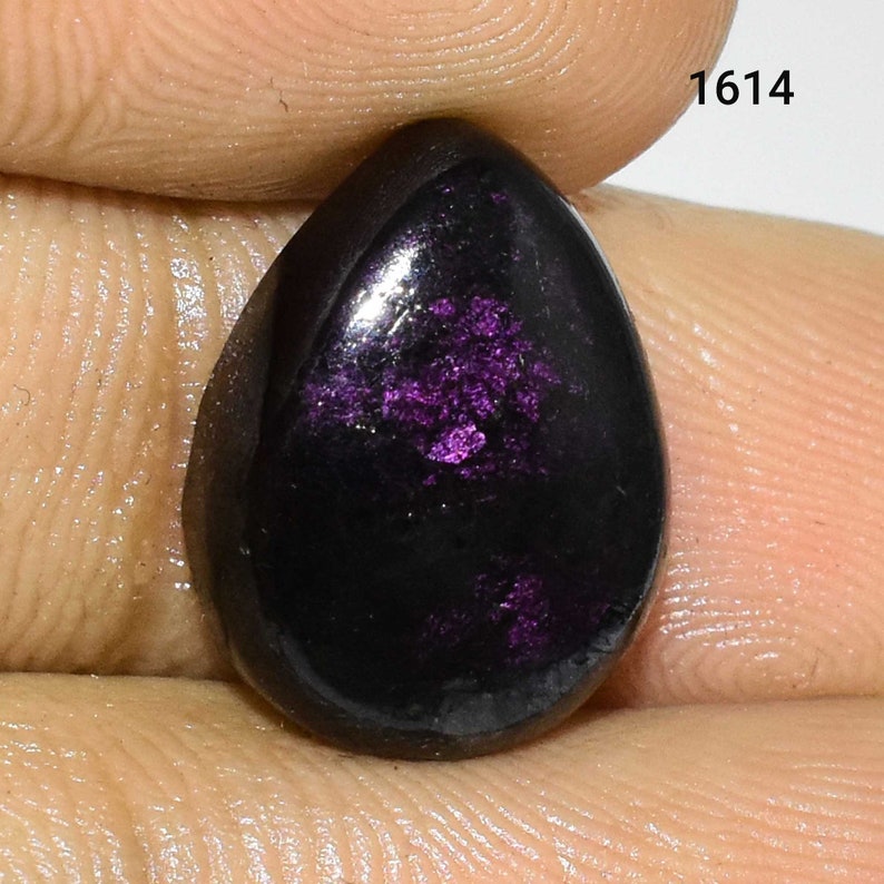 K&ouml;nnte beinhalten: Ein tropfenf&ouml;rmiger Edelstein mit schwarzer Basis und violettem, irisierendem Schimmer. Der Edelstein ist etwa 1,5 cm lang.