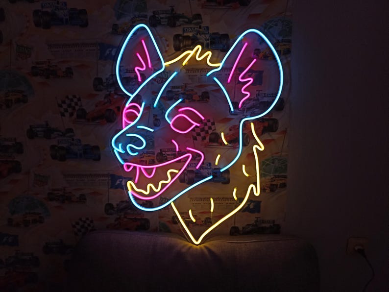 May include: A neon sign in the shape of a hyena's head, with a blue outline and pink and yellow accents. The sign is mounted on a wall with a racing car wallpaper.