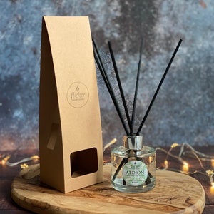 May include: A clear glass bottle diffuser with black reeds and a brown cardboard box. The bottle has a silver cap and a label that reads "Flicker Candle Studio" and "AEDION - Wild Mint & Eucalyptus".
