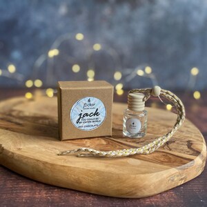 Könnte beinhalten: Eine kleine braune Schachtel und eine klare Glasflasche mit einem Holzverschluss liegen auf einem Holzservierbrett. Auf der Schachtel steht "jack YOU COULD BE MY ENTIRE WORLD HOT CHOCOLATE". An der Flasche ist eine geflochtene Kordel befestigt.