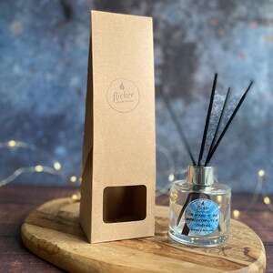 Könnte beinhalten: Eine klare Glas-Diffusorflasche mit schwarzen Schilfrohren und einem silbernen Kragen, neben einer braunen Pappschachtel. Die Flasche hat ein Etikett mit dem Text "I'm afraid of the unpredictability of existing". Die Box hat ein Logo mit der Aufschrift "flicker candle studio".
