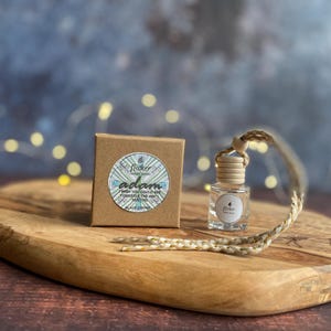 Könnte beinhalten: Eine kleine, klare Glasflasche mit Holzverschluss und geflochtener Kordel, neben einer kleinen braunen Schachtel. Die Schachtel hat einen runden Aufkleber mit dem Namen "adam" und dem Text "Finish you could see yourself the way I see you".