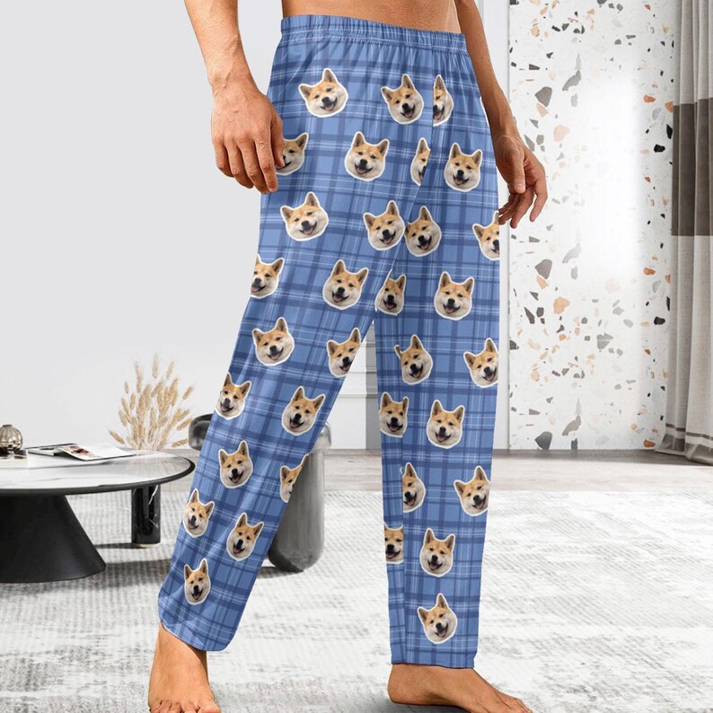 May include: Blue pyjama trousers with a plaid pattern featuring a repeated image of a dog's face.