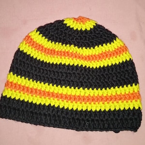 Puede incluir: Gorro de punto negro con rayas amarillas y naranjas.