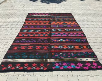 Pode incluir: Um tapete retangular longo com padrões geométricos em preto e cores. O tapete é feito de tecido tecido.