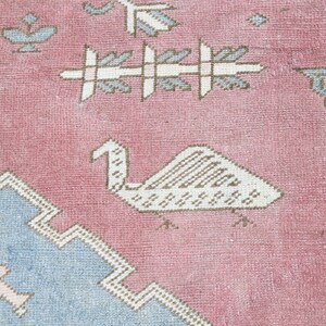 May include: A pink and blue rug with a geometric pattern. The rug features a stylized bird design in the center.