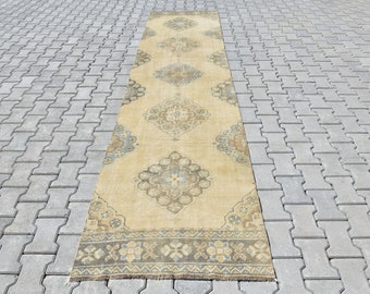 May include: A long, beige runner rug with a traditional Persian design in shades of blue, brown, and cream. The rug has a fringed edge and is laid out on a gray concrete patio.