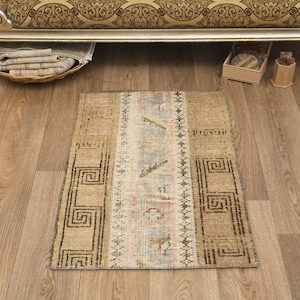May include: A small, rectangular rug with a beige background and brown geometric patterns. The rug has a faded, vintage look and is perfect for adding a touch of bohemian style to any room.